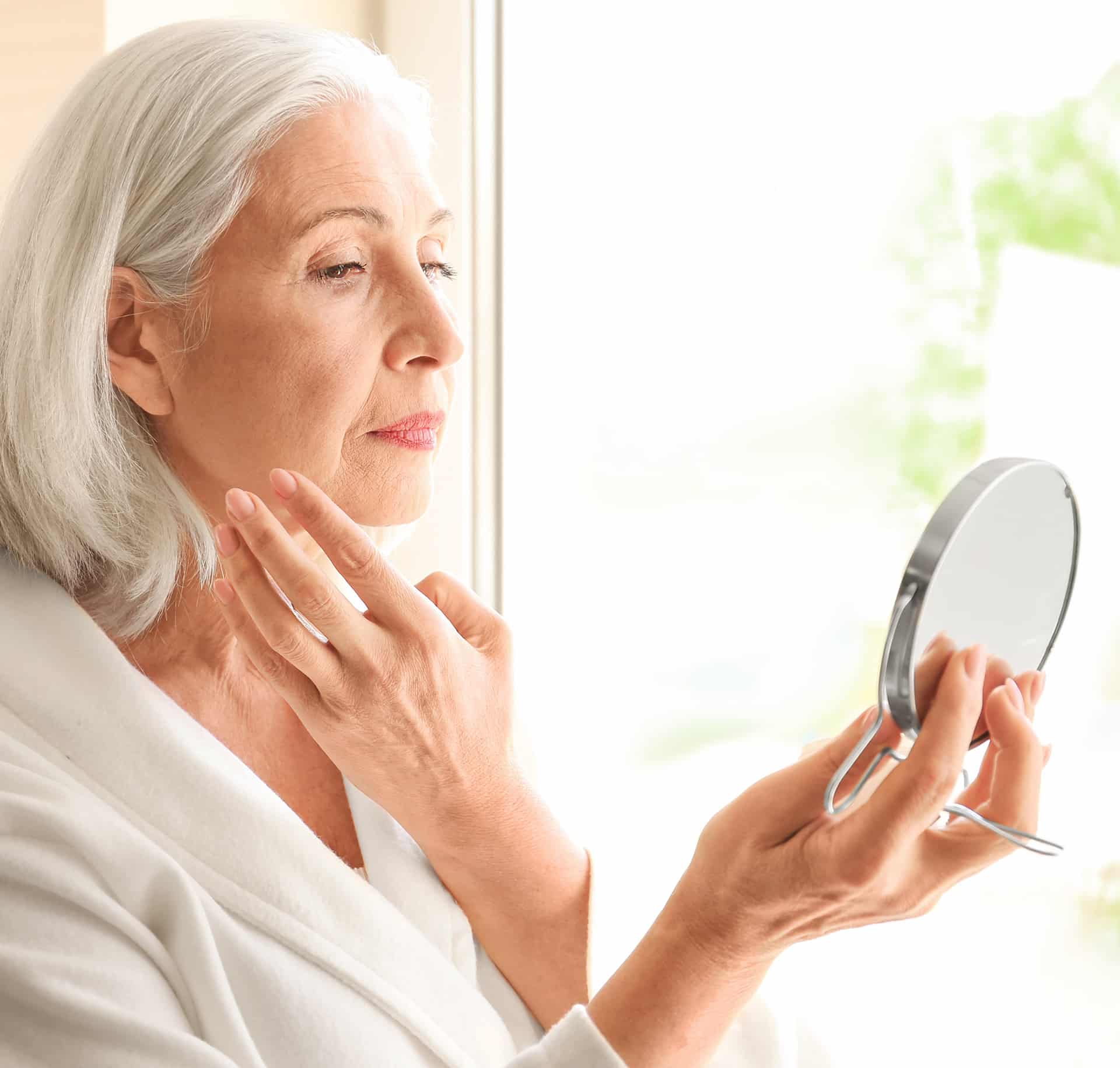 Services_Cosmetic elder woman looking into a mirror after cosmetic skin treatment at rocklin dermatology